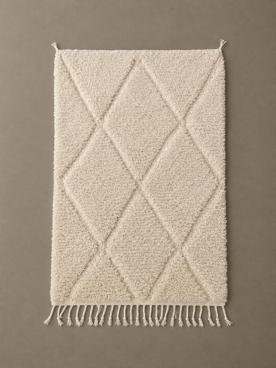 Handmade cream Moroccan Berber wool rug with a diamond pattern and fringed edges.