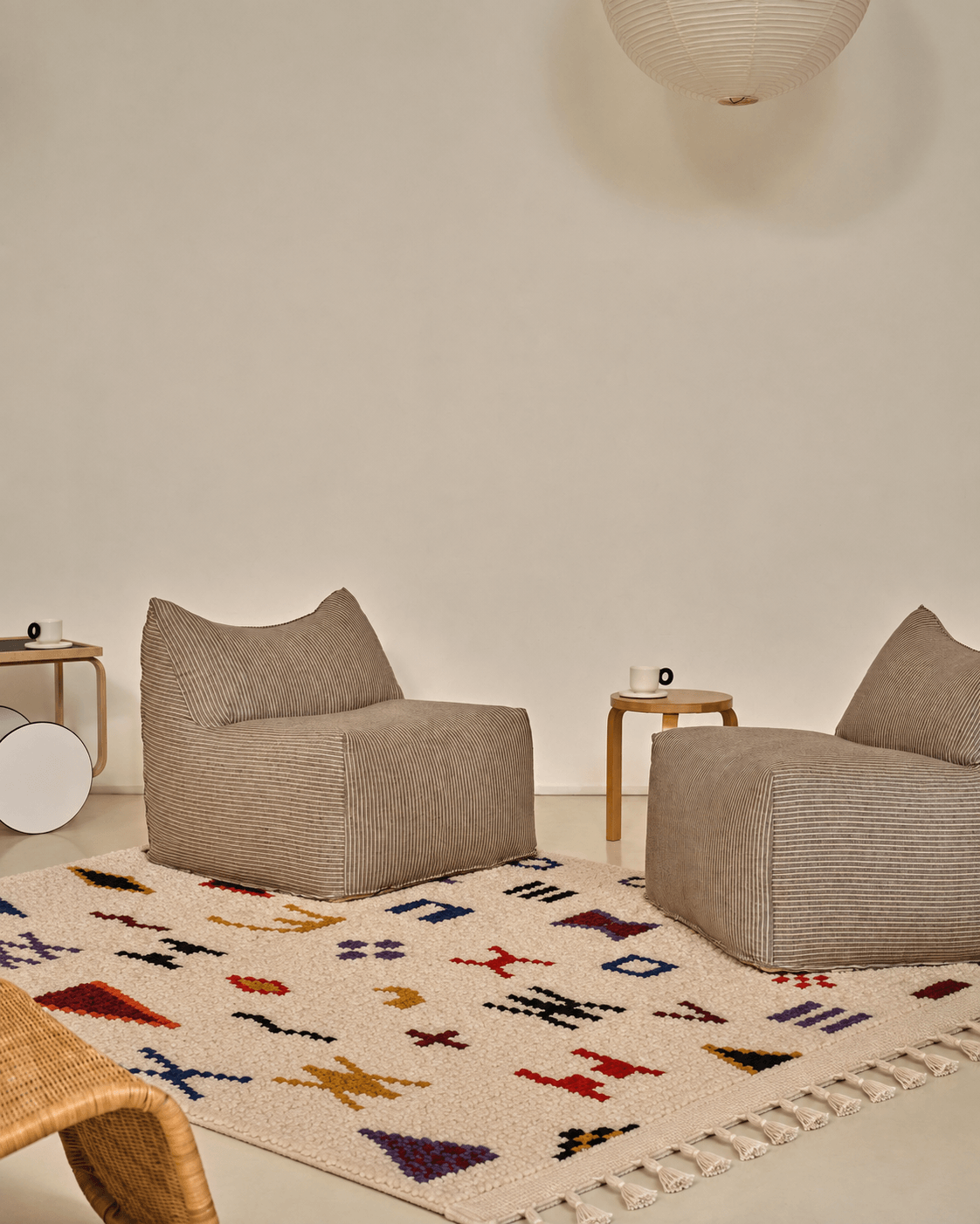 Azilal Contemporain  — Tapis Berbère marocain Two grey textured armchairs on a handmade Moroccan Berber wool rug with colorful patterns.